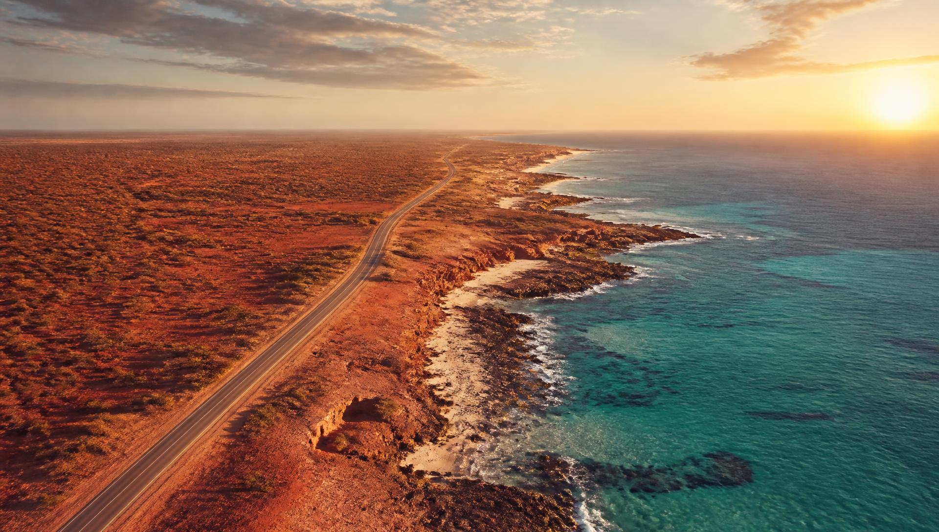 Aerial view of the Australian outback meeting a turquoise coastline at sunset